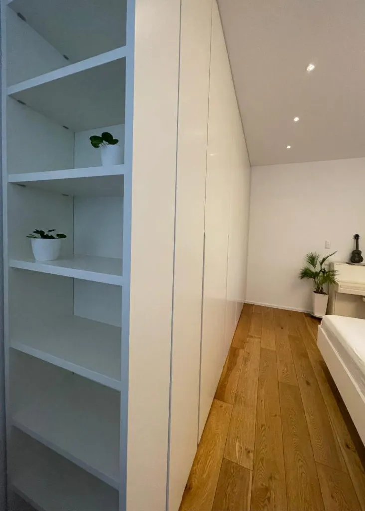 Customized wardrobe with a side library - Speyer, Germany - RAL9010 matte lacquered with integrated handles