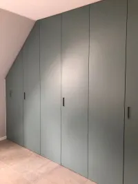 Slopping roof wardrobe: every roof has a different slope, so we offer our configurator, which adapts perfectly to your measurements to create a practical and functional design wardrobe customized to your needs. Everything is neatly enclosed behind personalized color doors. This wardrobe is installed in our customer&rsquo;s house in Vienna, Austria – FB 85 Oval Room Blue matte lacquered with integrated handles S1.