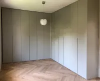 Custom-made corner built-in wardrobe: personalized color, dimensions, and designed by our client to fit perfectly in their bedroom – Düsseldorf, Germany – matte lacquered in RAL7044 with integrated handles. 

This wardrobe has varying depths to cover a chimney column and close it off with doors, creating a single, uniform surface.