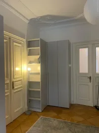 Custom corner wardrobe with side library: the modern, design wardrobe perfectly matches the old-style apartment in the center of Berlin in Germany - RAL7047 matt lacquered with integrated handles.

The side library, matching this corner wardrobe in color, adds a stylish and cohesive look to the space. It’s ideal for displaying plants, handbags, books, or decorative items like photo frames, art pieces, or even small storage baskets, seamlessly combining the functionality of the room with elegant design.