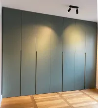 Customized wardrobe: Installed in our customer&rsquo;s bedroom in Berlin, Germany, this green color varies depending on the light (daylight or artificial lighting).

With warm lighting in the room and reflections from the wooden floor, it takes on a soft, warm green hue (as shown in the picture), creating a cozy and naturally peaceful atmosphere for relaxation.

This wardrobe is finished in FB 47 green smoke matte lacquer with integrated handles.

The exact dimensions of this wardrobe are 350.7 cm in width, 266 cm in height, and 61 cm in depth.